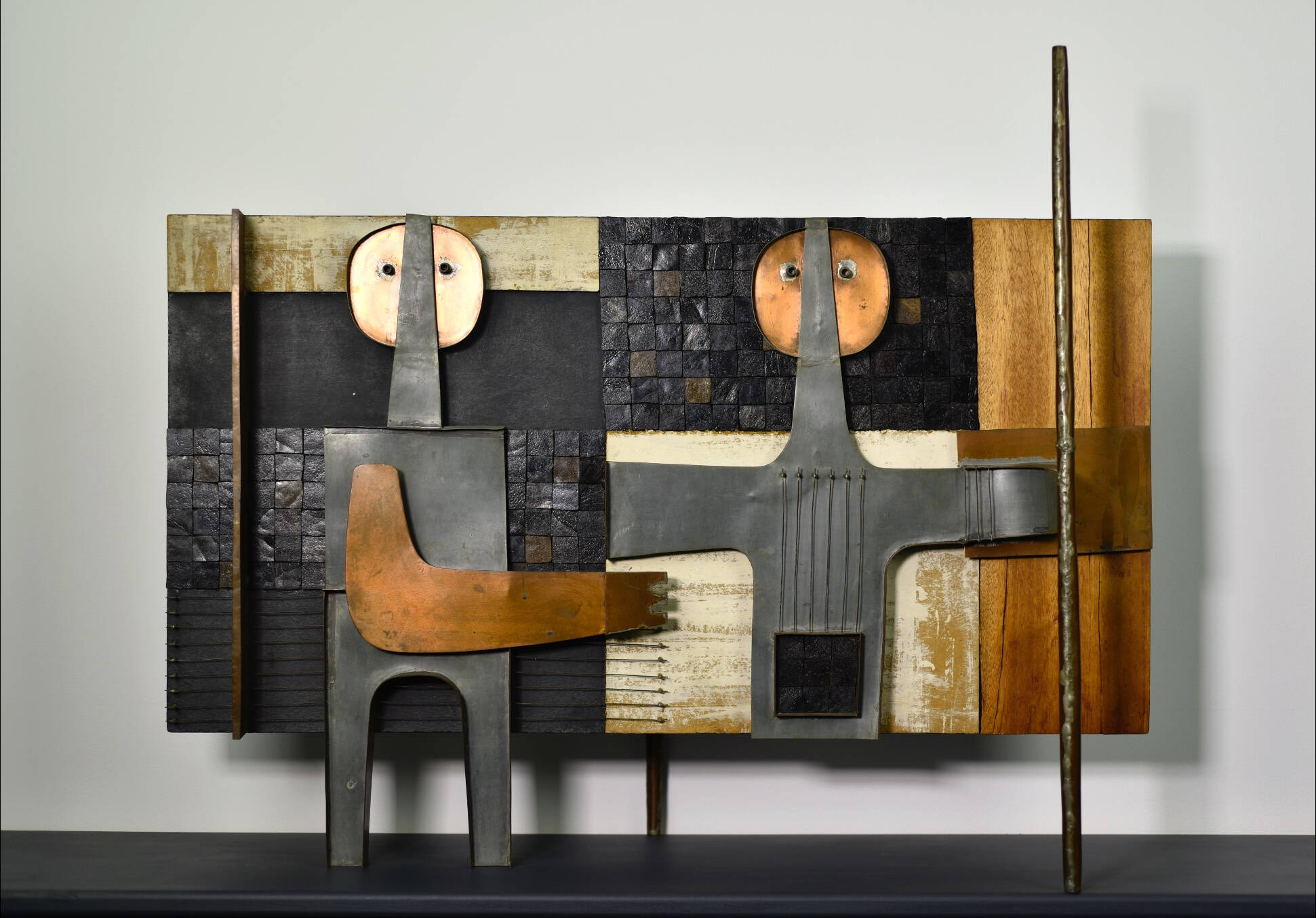 Mixed media sculpture of two abstract figures side by side, one reaching towards the other.